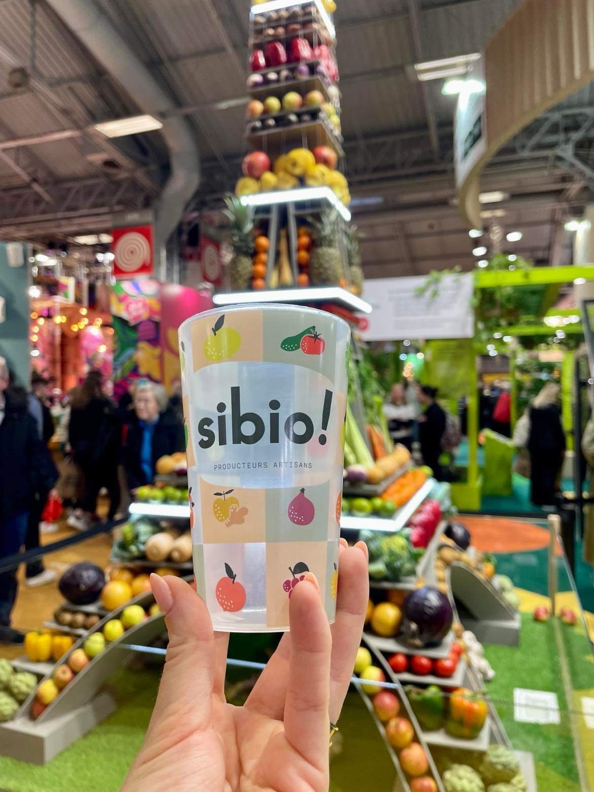 Gobelet réutilisable personnalisé tenu en main sur un salon